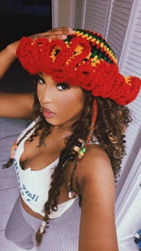 a woman wearing a crocheted hat with dreadlocks