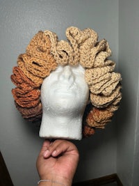 a mannequin holding a crocheted afro hat