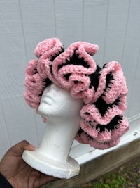a mannequin wearing a pink and black crocheted hat