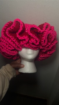 a person holding a pink crocheted hat
