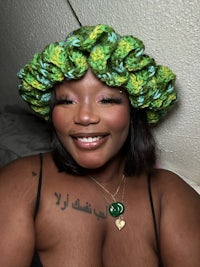 a black woman wearing a green crocheted crown