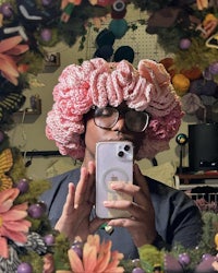 a woman taking a selfie with a crocheted flower hat