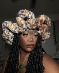 a woman with dreadlocks wearing a furry hat